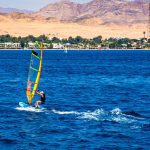 man with extreme windsurfing sport blue sea with sand beach background
